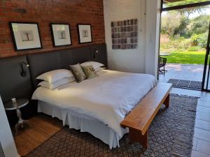 ein Schlafzimmer mit einem Bett mit einer Bank daneben in der Unterkunft Liedjiesbos Urban Olive Farm in Bloemfontein