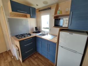 a small kitchen with blue cabinets and a white refrigerator at Smart Home Paris mit Terrasse, Europapark, Rulantica 15min in Boofzheim