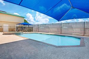 a swimming pool with a blue umbrella next to a fence at Days Inn by Wyndham San Antonio Airport in San Antonio