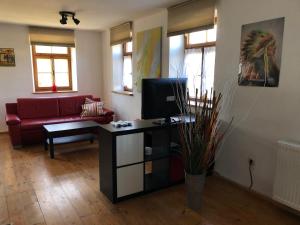 ein Wohnzimmer mit einem roten Sofa und einem TV in der Unterkunft Alte Wirtschaft in Hohenlinden