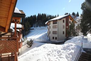 a house with snow on the ground next to a building at Alphome Flums in Flumserberg