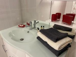 La salle de bains blanche est pourvue d'un lavabo et d'un miroir. dans l'établissement Le Gîte les Châtaignes, à Volvic
