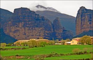 una montaña con un pueblo frente a un campo verde en Casa Lino Huesca, en Chibluco