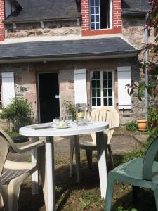 a white table and chairs in front of a house at Maison dans la prairie in Plurien