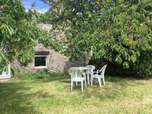 two chairs and a table under a tree at Maison dans la prairie in Plurien