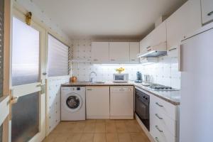 a kitchen with white cabinets and a washer and dryer at Apartament Greta in L'Escala