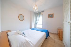 a bedroom with a white bed and a window at Apartament Greta in L'Escala +12 photos