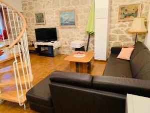 un soggiorno con un divano e una televisione di Old stone house VICKO a Podgora