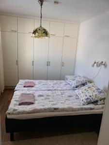 een slaapkamer met een bed met witte kasten en een kroonluchter bij Huoneistomajoitus Hella Härmä in Härmä