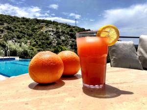 Un vaso de jugo de naranja sobre una mesa con dos naranjas. en Villa Valo, en Kalkan