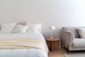 a white bedroom with a bed and a chair at Yksiö rauhallisella ja keskeisellä sijainnilla in Helsinki
