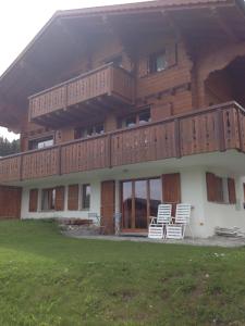 ein großes Haus mit zwei Liegestühlen im Hof in der Unterkunft Chalet Lucille in Leysin