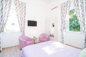 a bedroom with pink chairs and a bed and a tv at House Boninovo in Dubrovnik
