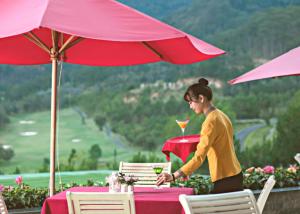 a woman sitting at a table with a drink at Swiss-Belresort Tuyen Lam in Da Lat