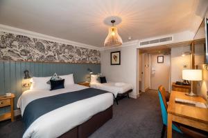 a hotel room with two beds and a desk at Greswolde Arms by Chef & Brewer Collection in Solihull