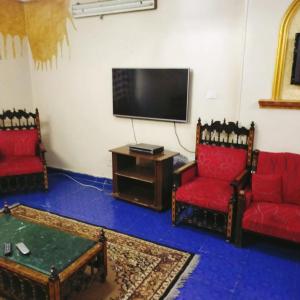 a living room with two red chairs and a flat screen tv at Elredy's apartments the blue edition in Cairo