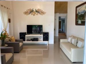 sala de estar con TV de pantalla plana y sofá en BALAI BANAHAW Vacation Farm and Private Resort en Lucban