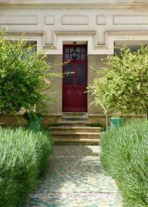 a red door on a house with stairs and bushes at La Villa de Chinon in Chinon