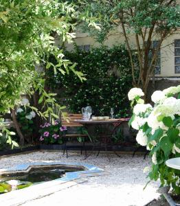 a table and bench in a garden with flowers at La Villa de Chinon in Chinon