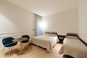a bedroom with two beds and a table and chairs at Albergo Italia in Matera