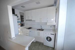 カディスにあるAtico Apartamento Loft Playa Victoria Cadizのキッチン(白いキャビネット、洗濯機付)