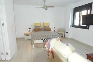 a white bedroom with a bed and a couch at Acogedor apartamento en la playa de Cádiz in Cádiz