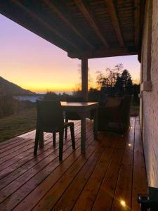 un tavolo e sedie su una terrazza in legno con il tramonto di Votre studio balnéo bien-être à la montagne a Thollon