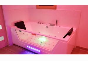 ein rosa Badezimmer mit einer beleuchteten Badewanne in der Unterkunft Votre studio balnéo bien-être à la montagne in Thollon