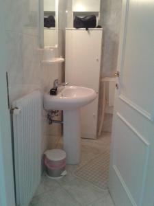W białej łazience znajduje się umywalka i lustro. w obiekcie Villa Giulia w Grado