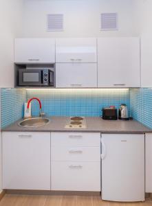 a kitchen with white cabinets and a sink at Stylish studio Dare next to the City walls in Dubrovnik