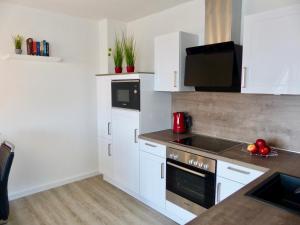 a kitchen with white cabinets and a stove top oven at Petten Beach 17 in Petten