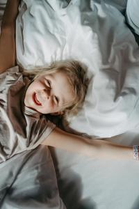 Basekamp Mountain Budget Hotel في كاتشبيرغوهي: فتاة صغيرة مستلقية على سرير مبتسمة