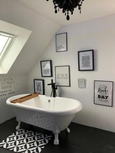 uma banheira branca num quarto com fotografias na parede em Cabana Lampaul em Lampaul-Plouarzel