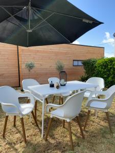 une table et des chaises blanches sous un parasol dans l'établissement Cabana Lampaul, à Lampaul-Plouarzel