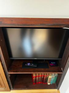 a television on a wooden shelf with books at Gästehaus Deisl in Mariapfarr