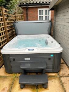 a hot tub sitting on a patio with a stool at Cromwell Lodge, Cromer, moments from the beach! in Cromer