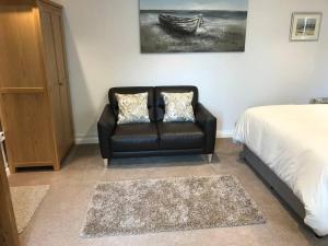 Schlafzimmer mit einem schwarzen Ledersessel und einem Bett in der Unterkunft Lovely detached garden chalet in Broadstone