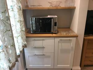 a microwave oven sitting on top of a counter at Lovely detached garden chalet in Broadstone