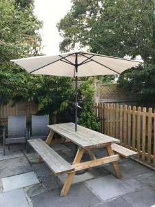 a wooden picnic table with an umbrella on a patio at Lovely detached garden chalet in Broadstone