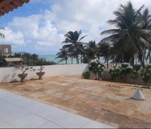 a patio with palm trees and the ocean in the background at Vista pro mar maravilhosa,Tibau-RN in Tibau