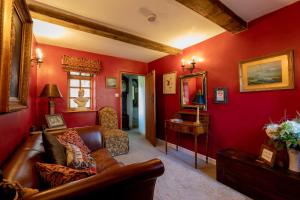 a living room with red walls and a leather couch at Blounts Court Farm in Devizes