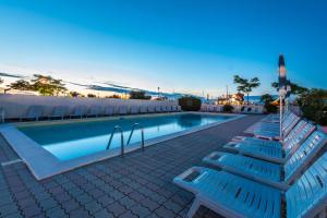basen z 2 niebieskimi ławkami obok niego w obiekcie Hotel Corinna w Rimini
