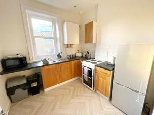 a kitchen with a white refrigerator and wooden cabinets at April Lodge The Chine- A Spacious Studio-Beach-Parking-Couples-Professionals-Long Stays in Bournemouth +8 photos