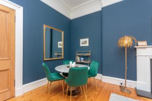 a dining room with blue walls and a table with green chairs at South Learmonth Gardens Apartment in Edinburgh +30 photos