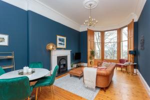 South Learmonth Gardens Apartment في إدنبرة: غرفة معيشة بجدران زرقاء وطاولة وكراسي