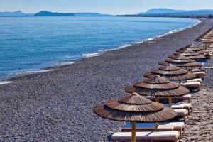 a row of beach umbrellas on a rocky beach at Aria apts 100 m from the beach by PosarelliVillas in Kolymvari