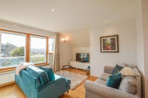 a living room with two couches and a television at Rowan Tree Apartment - A modern, quiet hideaway with sweeping views across Oban in Oban