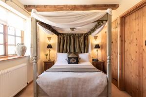 a bedroom with a four poster bed with a canopy at Blounts Court Farm in Devizes