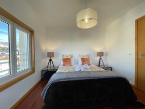 a bedroom with a bed with two pillows and a window at Miguel Torga Diamond Penthouse in Coimbra