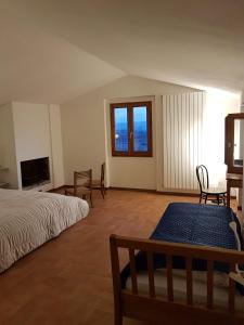 a bedroom with a bed and chairs and a window at Casa con piscina camino e biliardo in San Giustino Valdarno